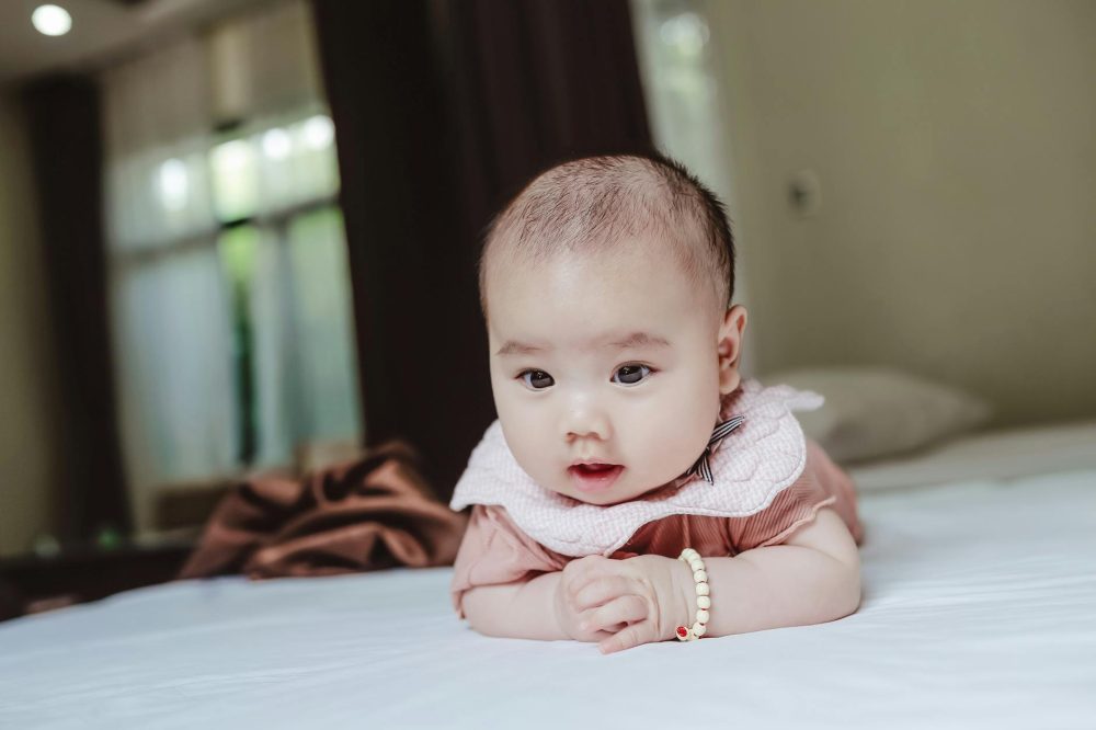 adorable newborn baby lying on stomach on bed