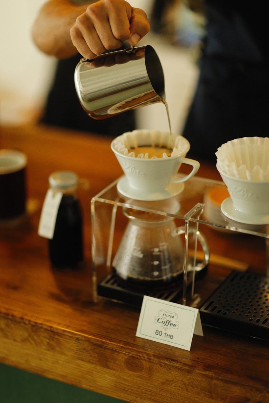 person pouring liquid into a brewed coffee